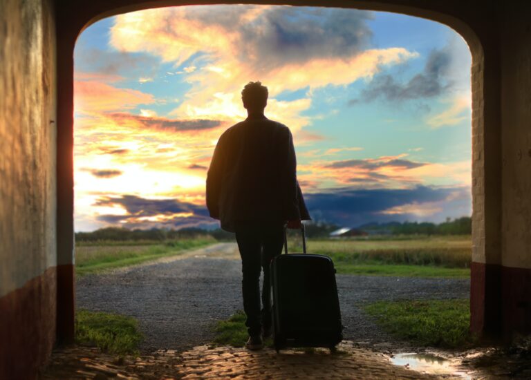 man with suitcase in hand looking of into the distance