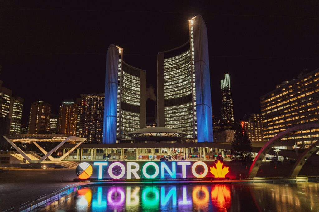 Night phono of the Toronto City Hall. The Toronto sign letters are all lite up in different colours.