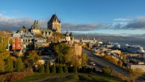 Photo of Quebec City with the Chateau Frontenac on the left and the St. Lawrence River below and cruise ships in port.